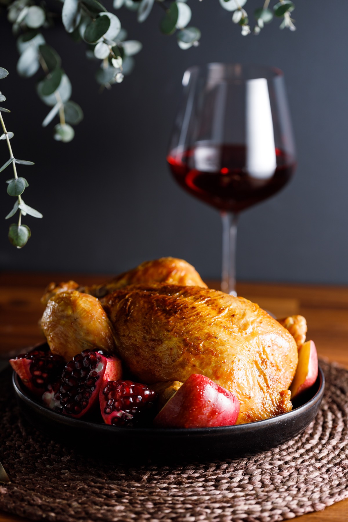 Whole roast chicken with pomegranate, apple and red wine served on a table