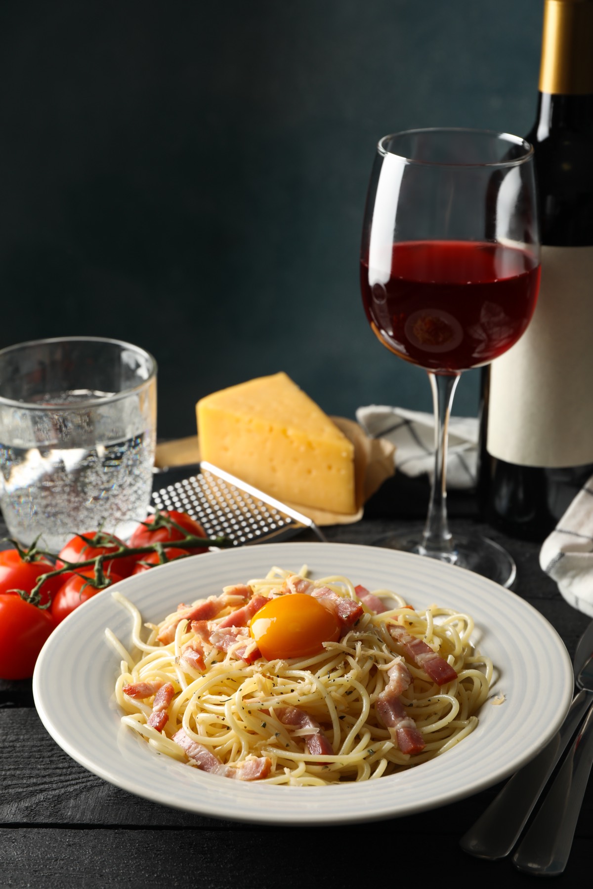 Une assiette de pâtes et un verre de vin rouge servis sur une table en bois