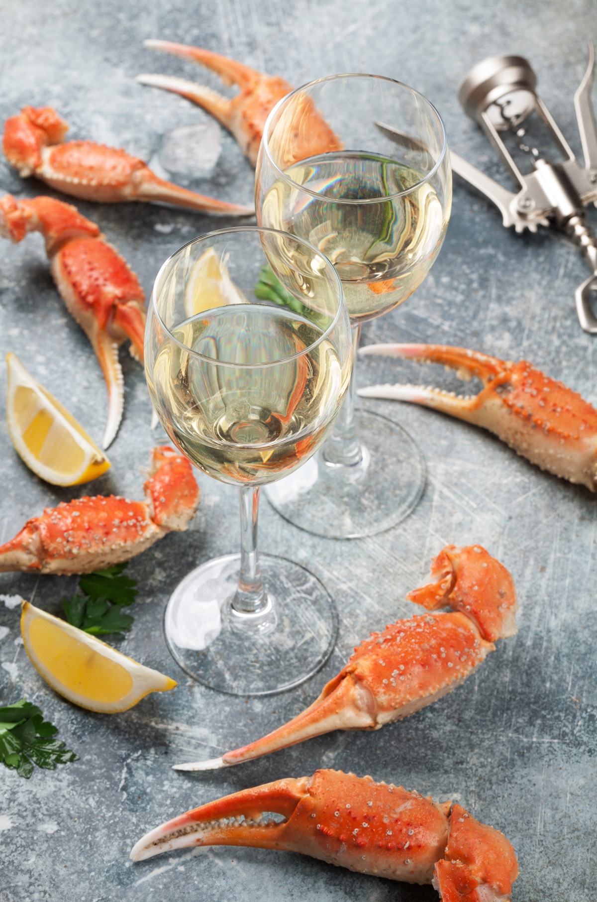 Lobster claws with lemons and two glasses of white wine served on a stone table