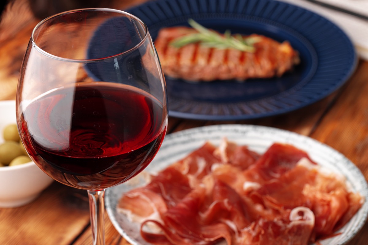 Saucisse de viande tranchée et vin rouge servis sur une table.