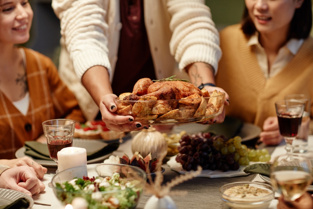 Close up of a woman serving roast turkey for dinner accompanied by red wine.