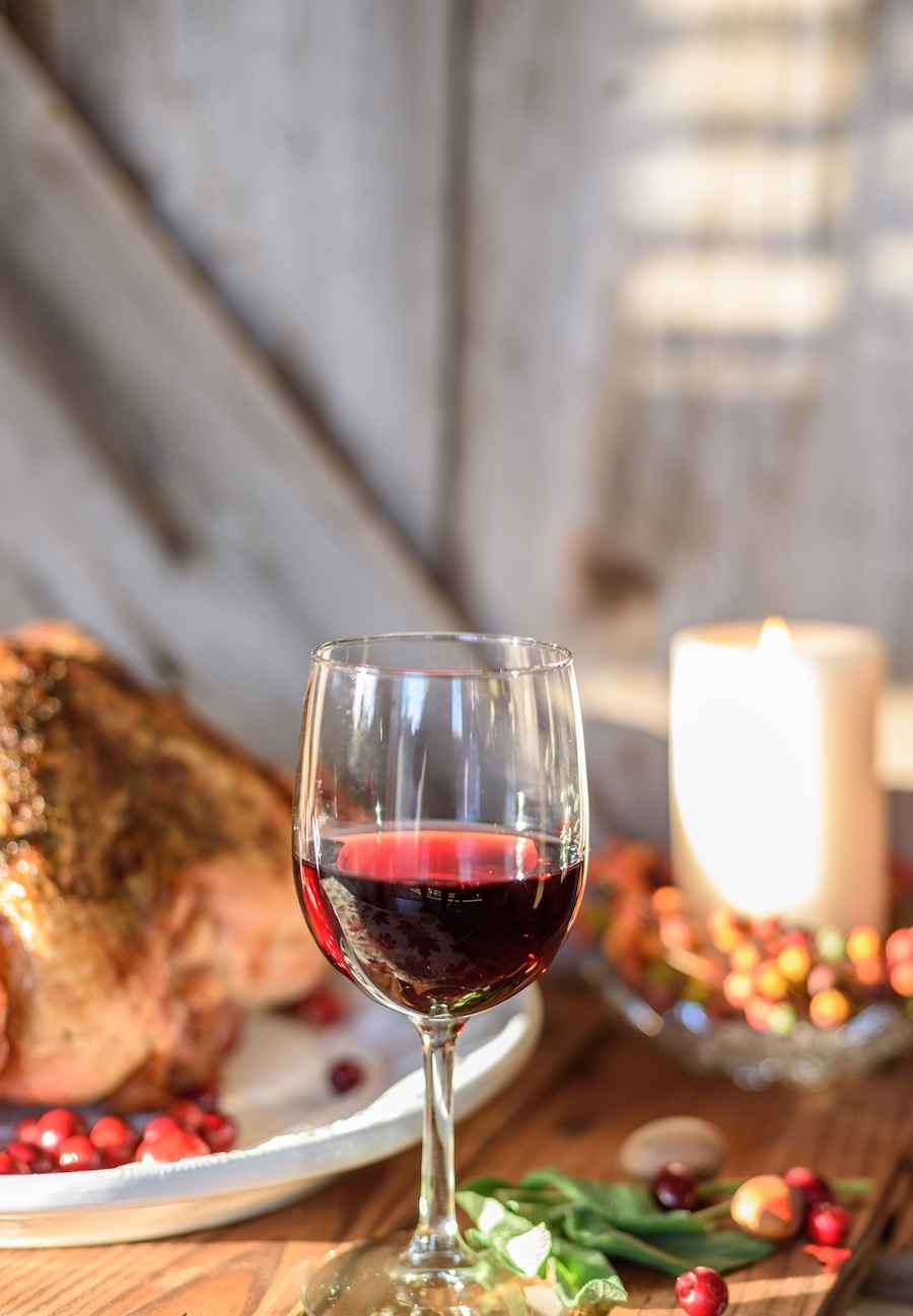 Un verre de vin rouge accompagné d'une dinde à l'arrière.