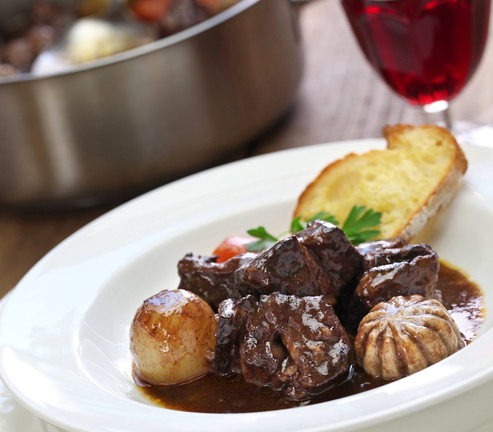 View of a beef bourguignon plate with red wine