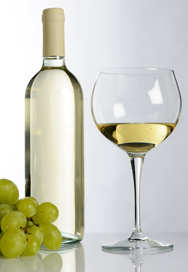 Wineglass with a bottle of white wine and grapes.